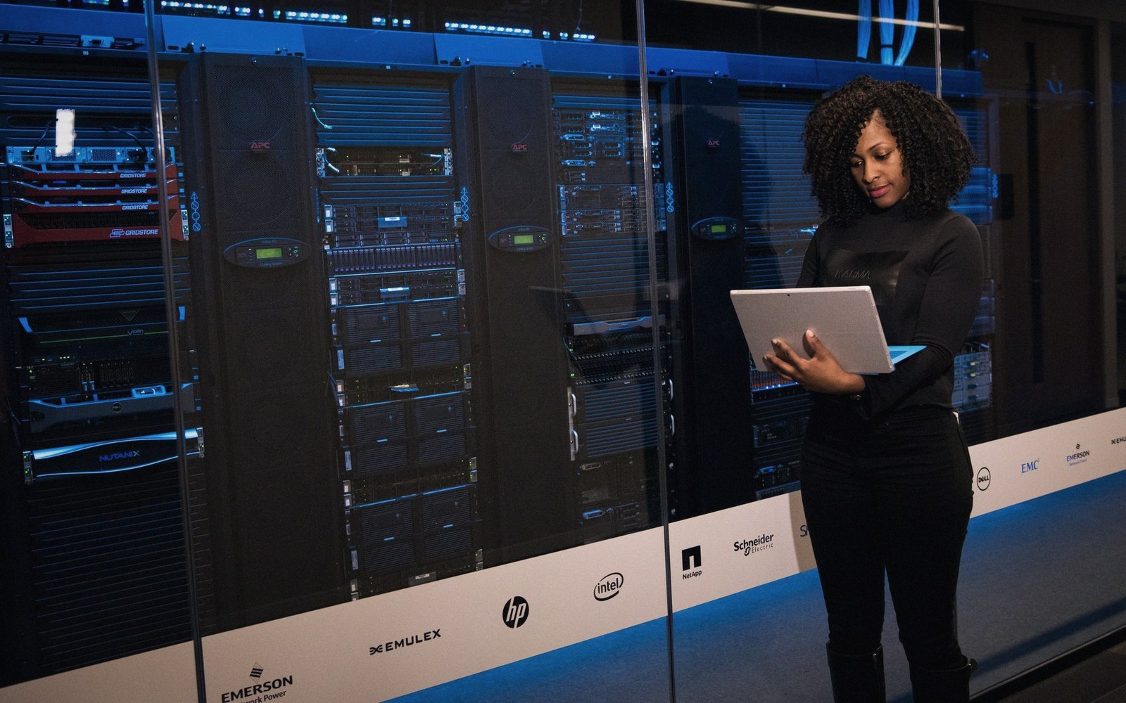 A laptop open on a raised access floor tile in a datacentre aisle, a rack visible in soft focus behind it